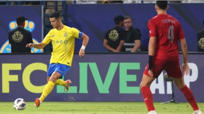 Penyerang Al Nassr asal Portugal, Cristiano Ronaldo berlari untuk menembak bola saat bek Duhail asal Qatar, Yousef Aymen coba menghadang selama matchday ketiga Grup E Liga Champions Asia 2023-2024 antara Al Nassr vs Al Duhail di Stadion Universitas King Saud di Riyadh